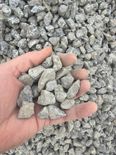 Load image into Gallery viewer, Hand holding small stones with a background of more stones