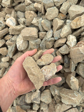 Load image into Gallery viewer, Hand holding a large stone amidst a pile of smaller stones