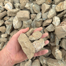 Load image into Gallery viewer, Hand holding a large stone amidst a pile of smaller stones