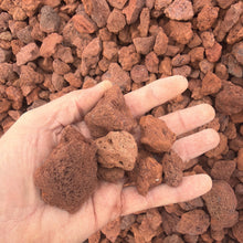 Load image into Gallery viewer, Hand holding red gravel with a background of more red gravel