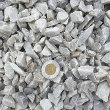 Load image into Gallery viewer, Close-up of small gray stones with a gold coin in the center.
