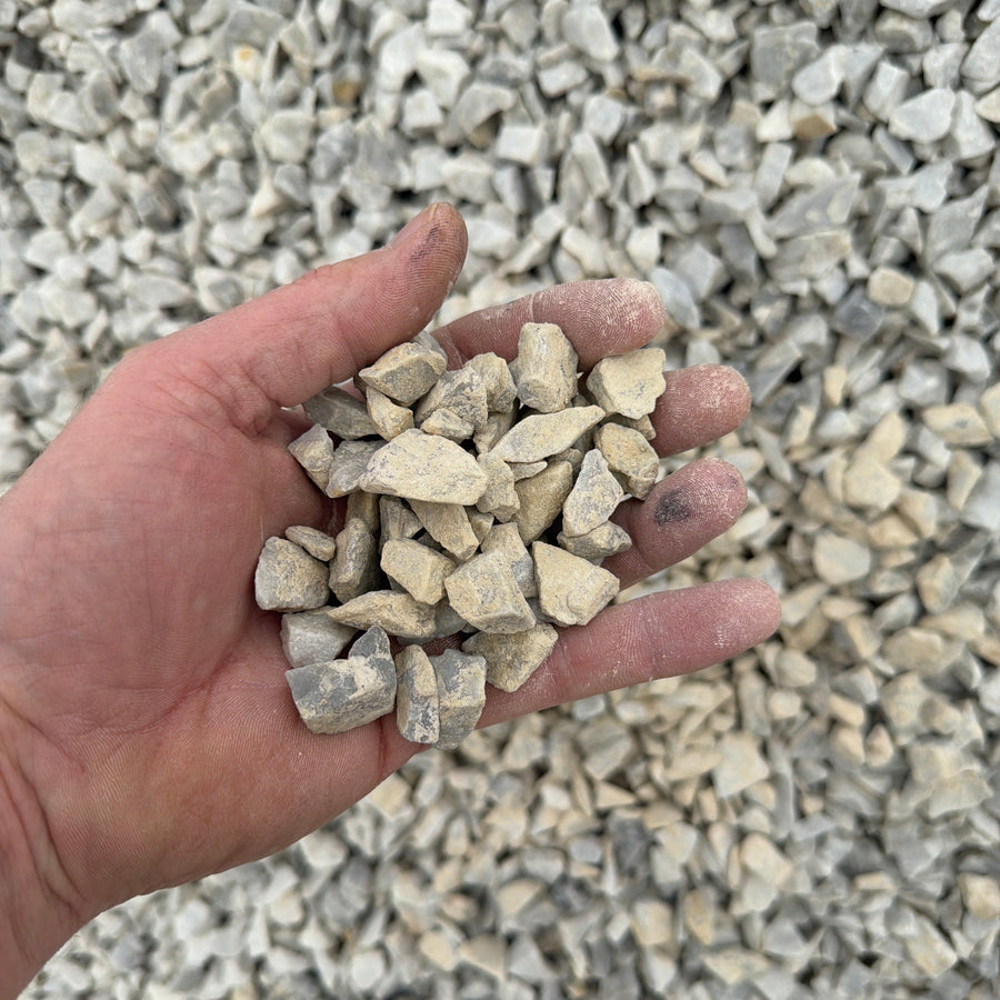 Hand holding small stones against a background of gravel