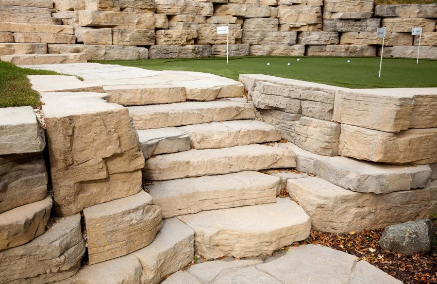 Stone steps leading up to a grassy area with a rock wall background